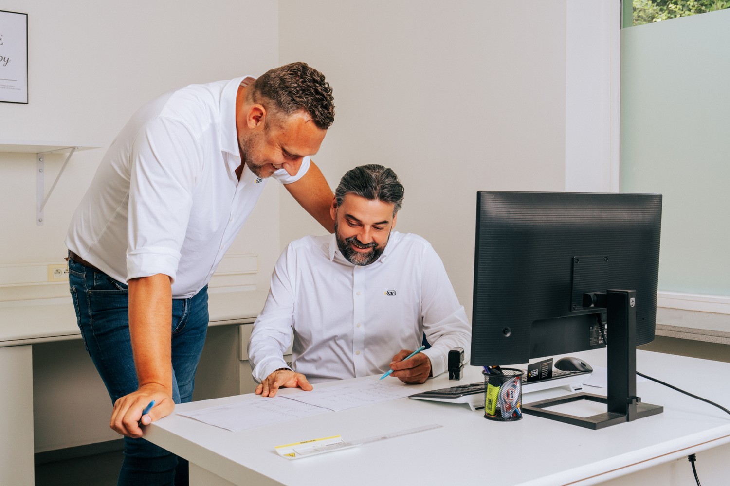 Tom Carlier en Olivier Vandenborre bekijken samen een document aan het bureau bij de pc