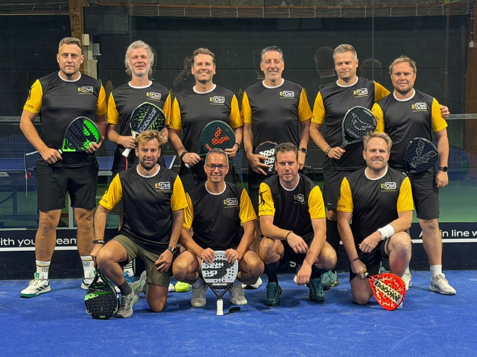 De door E-Ctrl gesponsorde padelgroep in nieuwe zwart-gele truitjes bij Arenal Waregem, in aanloop naar hun padelstage in Valencia.